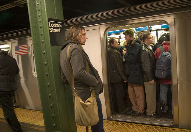 Courtesy is contagious, but it doesn't start with the guy on the right wearing his backpack on a packed train. (Photo via flickr user Runs With Scissors)